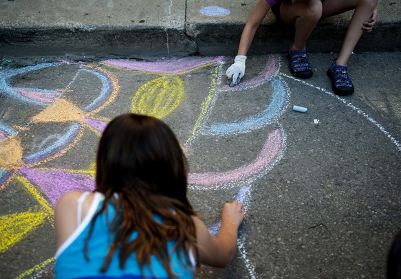 Anna Szalkowski, 12, and Sophie Motawi, 9, use chalk at the Huron River Water Trail tent to decorate sewage drains during the Mayor's Green Fair on Friday, June 16. Daniel Brenner I AnnArbor.com